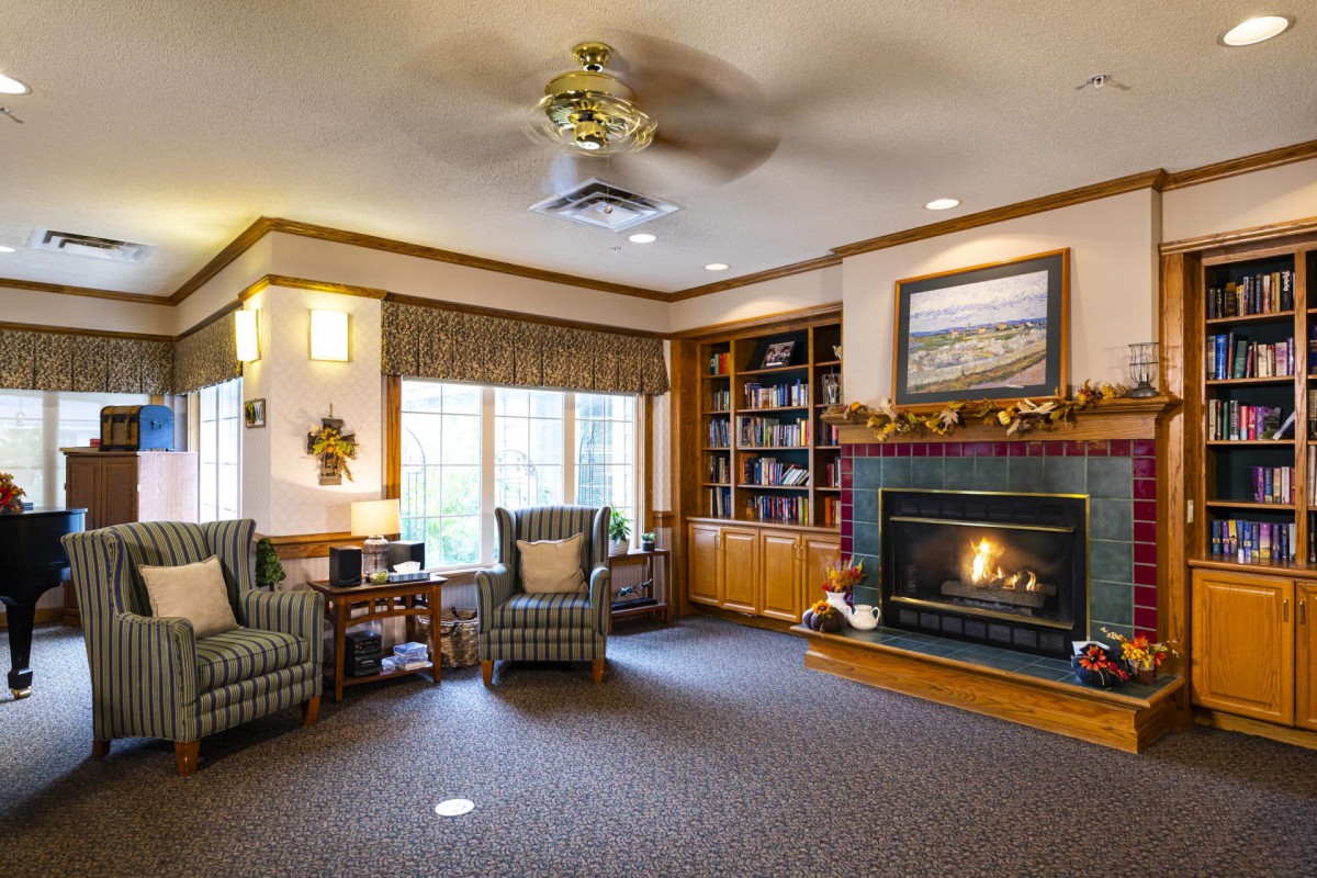 A cozy living room with a fireplace, bookshelves, and comfortable seating.