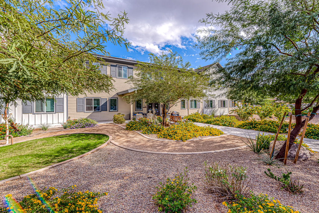 A beautiful house surrounded by a landscaped garden with trees and a clear blue sky.