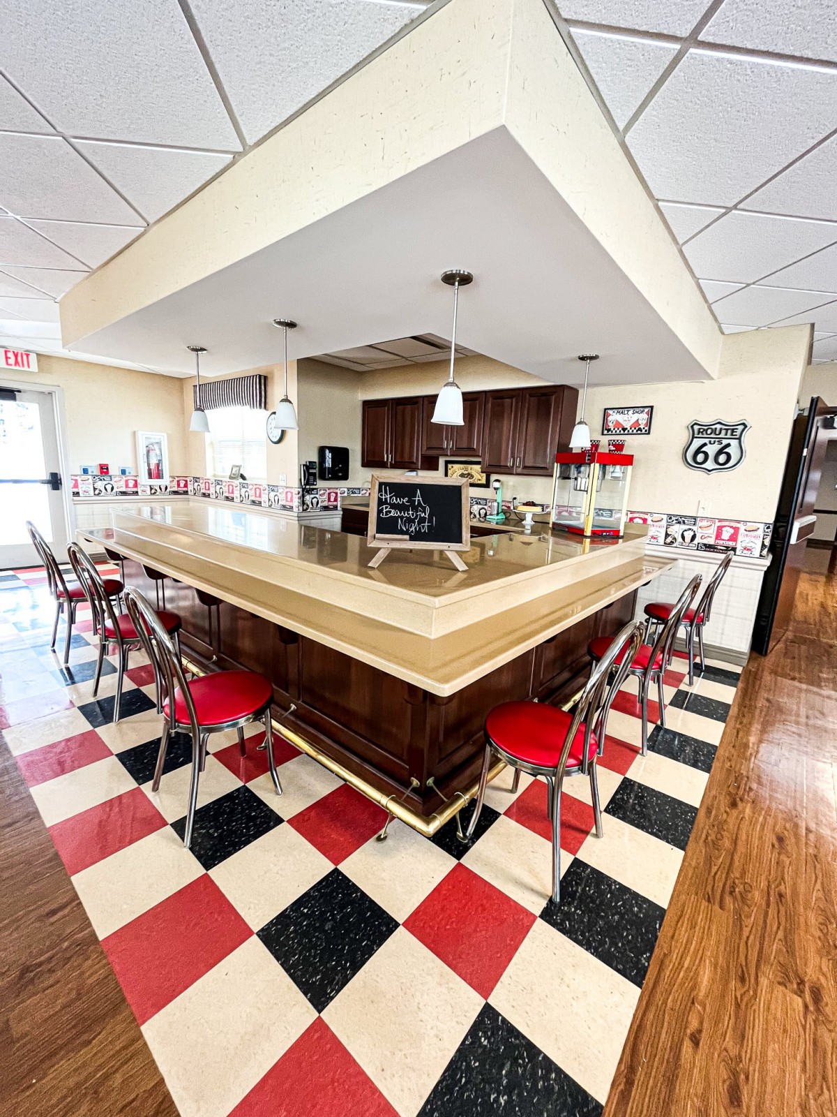 A retro-style diner with a checkerboard floor and bar seating arrangement.