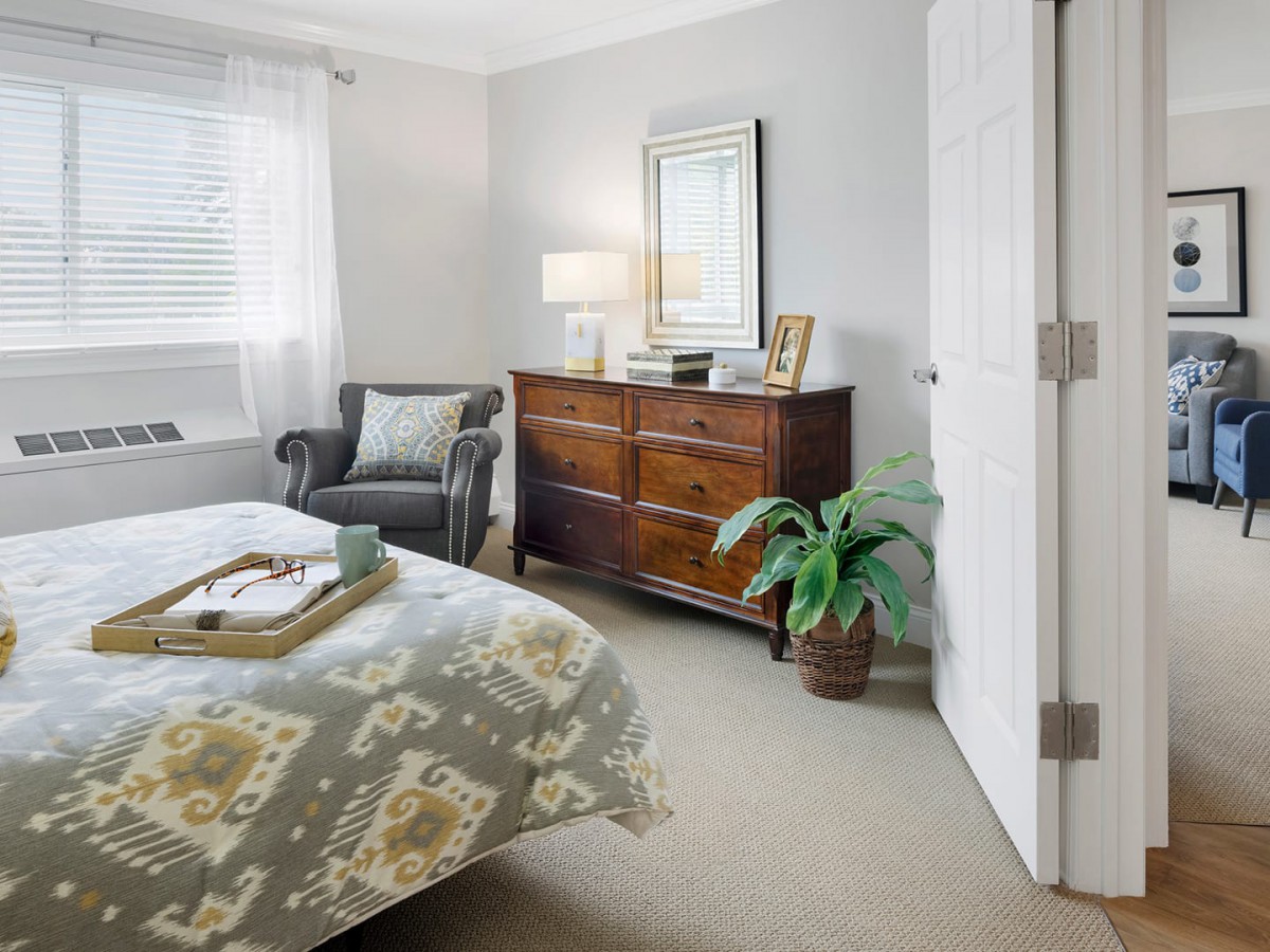 A cozy bedroom with a dresser, armchair, and stylish decor.