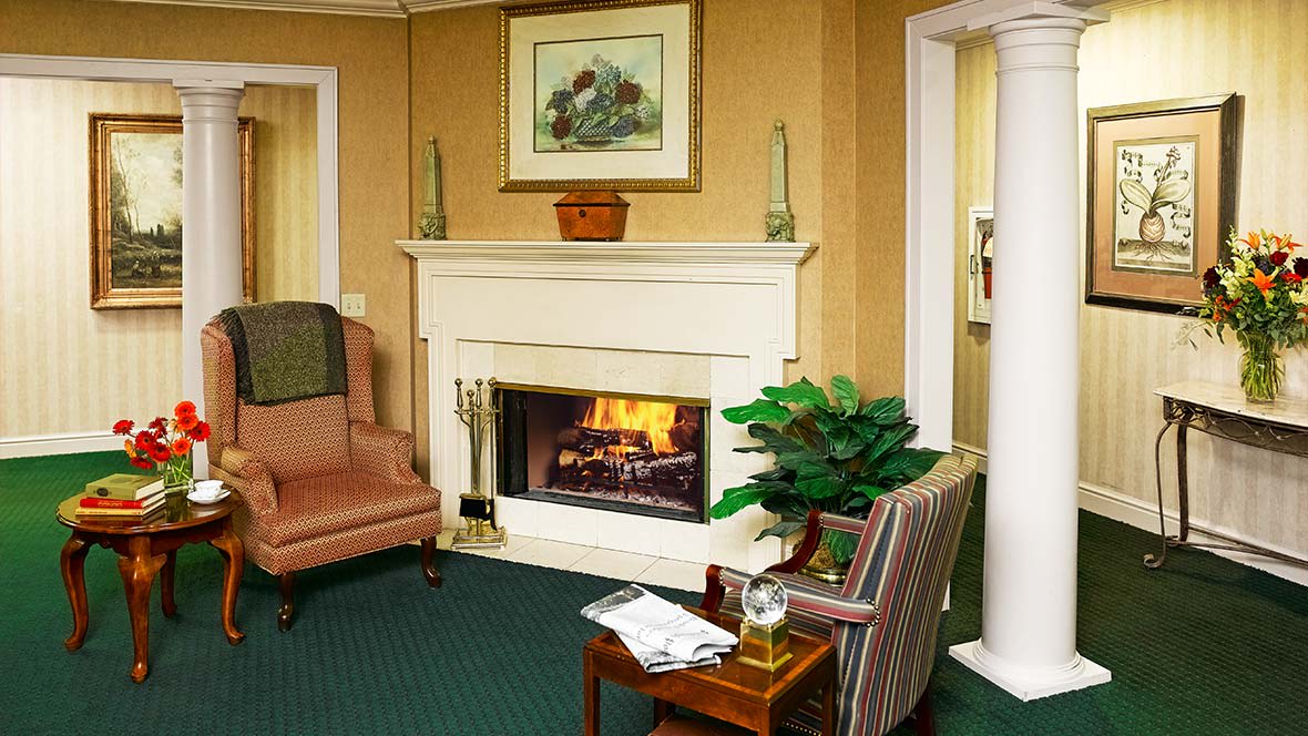 A cozy living room with a fireplace, armchairs, and decorative elements.