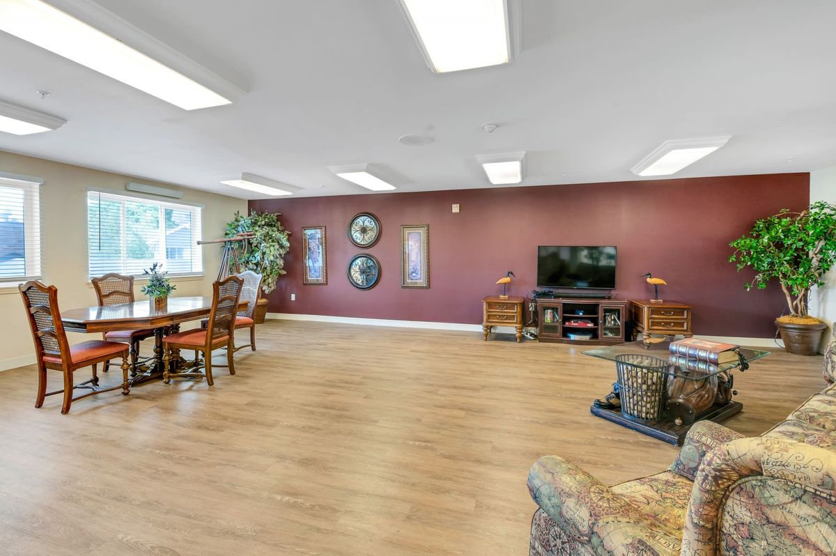 Spacious living room with hardwood flooring, featuring a television and decorative wall art.