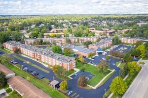 Aerial view of a suburban residential area with multiple buildings and parking lots surrounded by trees.