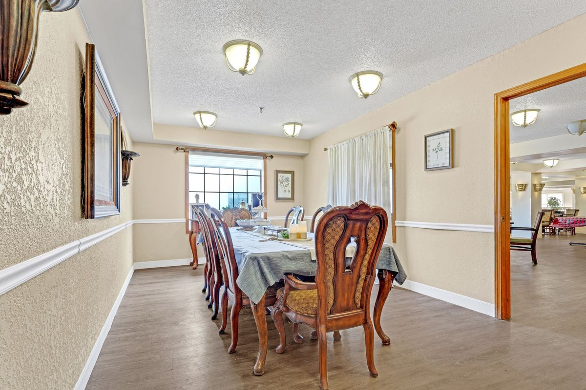 A well-lit dining room with a large table and elegant chairs, featuring ceiling lights and decor.