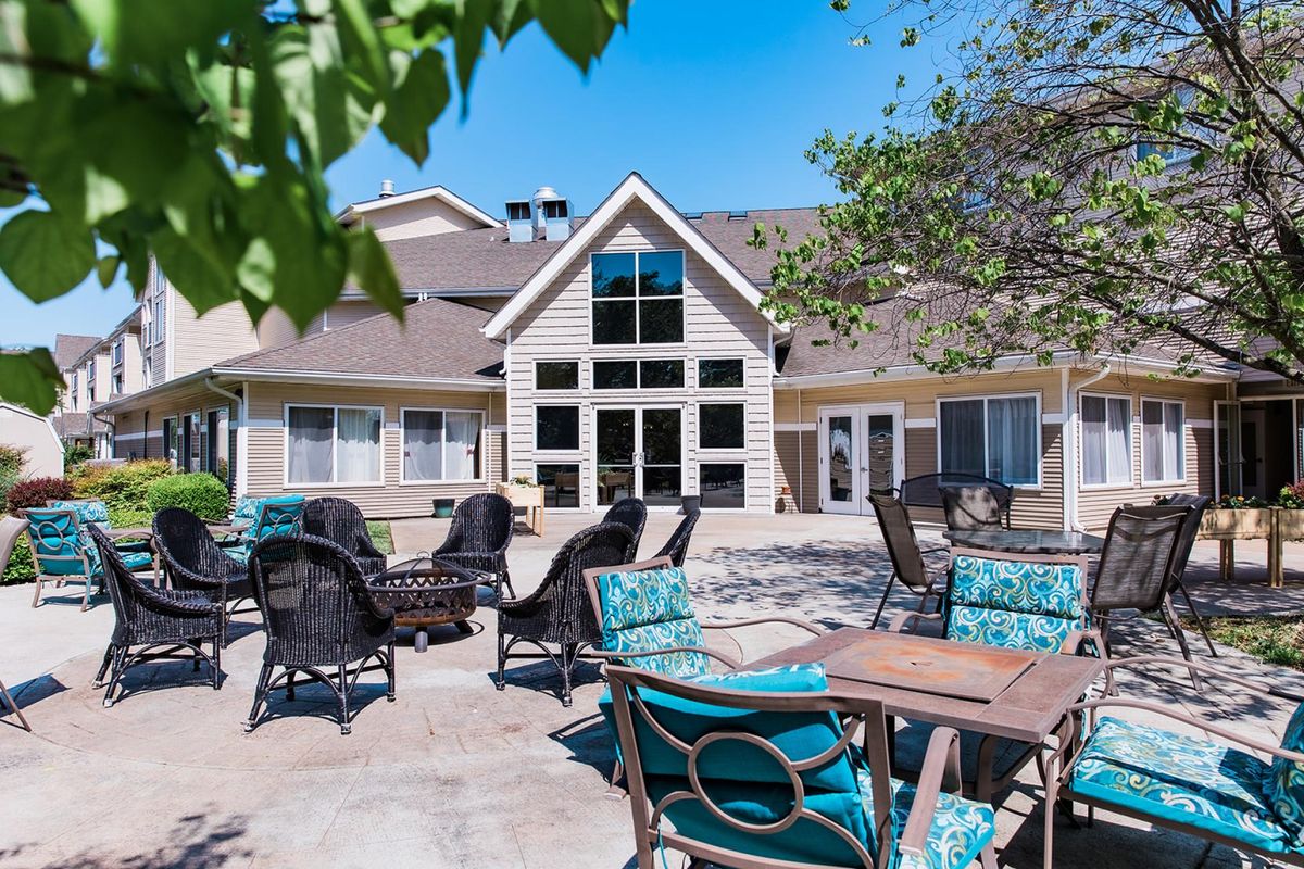 A sunny patio with comfortable seating in front of a modern residential building.