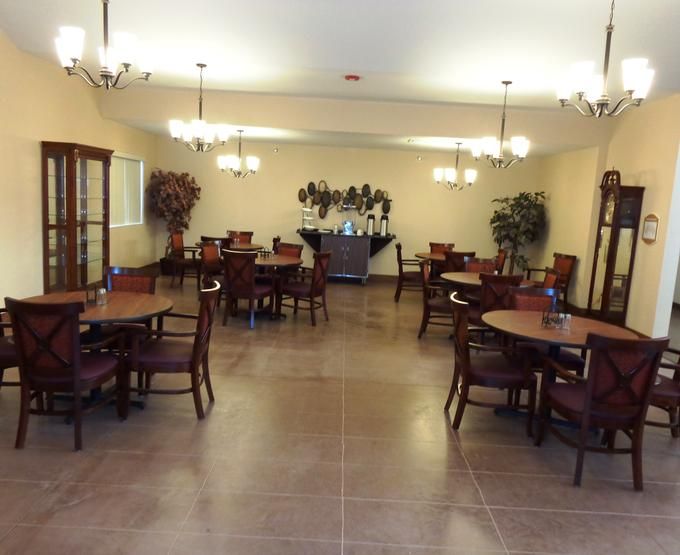 A spacious dining room with several tables and chairs, featuring warm lighting and elegant decor.