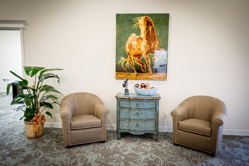 A cozy waiting area featuring comfortable seating, a stylish side table, and an eye-catching piece of artwork.