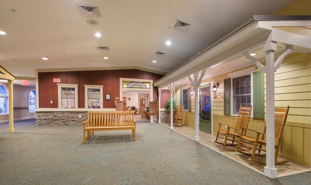 A cozy indoor seating area with benches and rocking chairs under soft lighting.