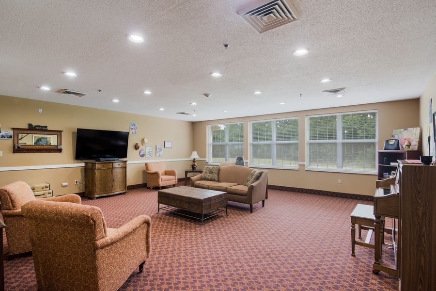 A spacious living room with sofas, a television, and large windows providing natural light.