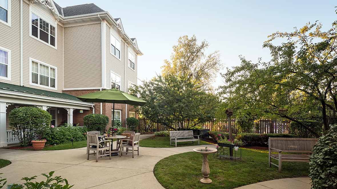 A cozy backyard with outdoor seating, lush trees, and a well-maintained lawn.