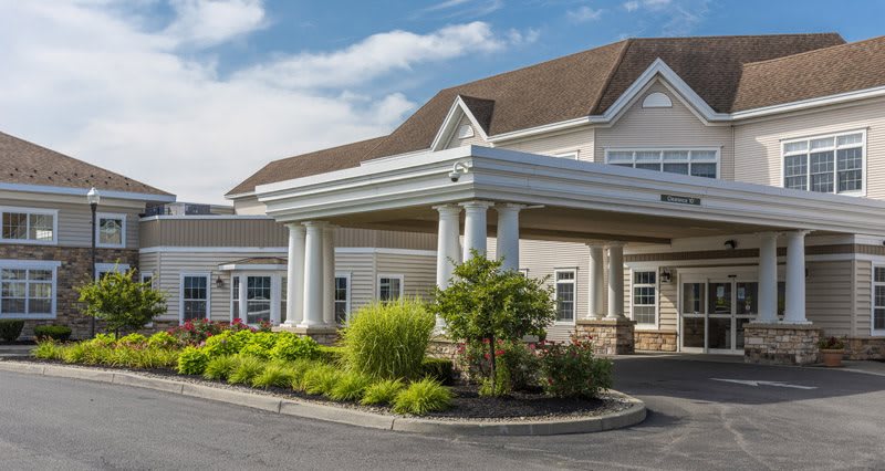 A well-maintained building entrance with columns and landscaped greenery.