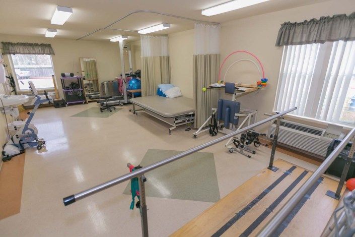 A physical therapy room equipped with parallel bars and rehabilitation equipment.