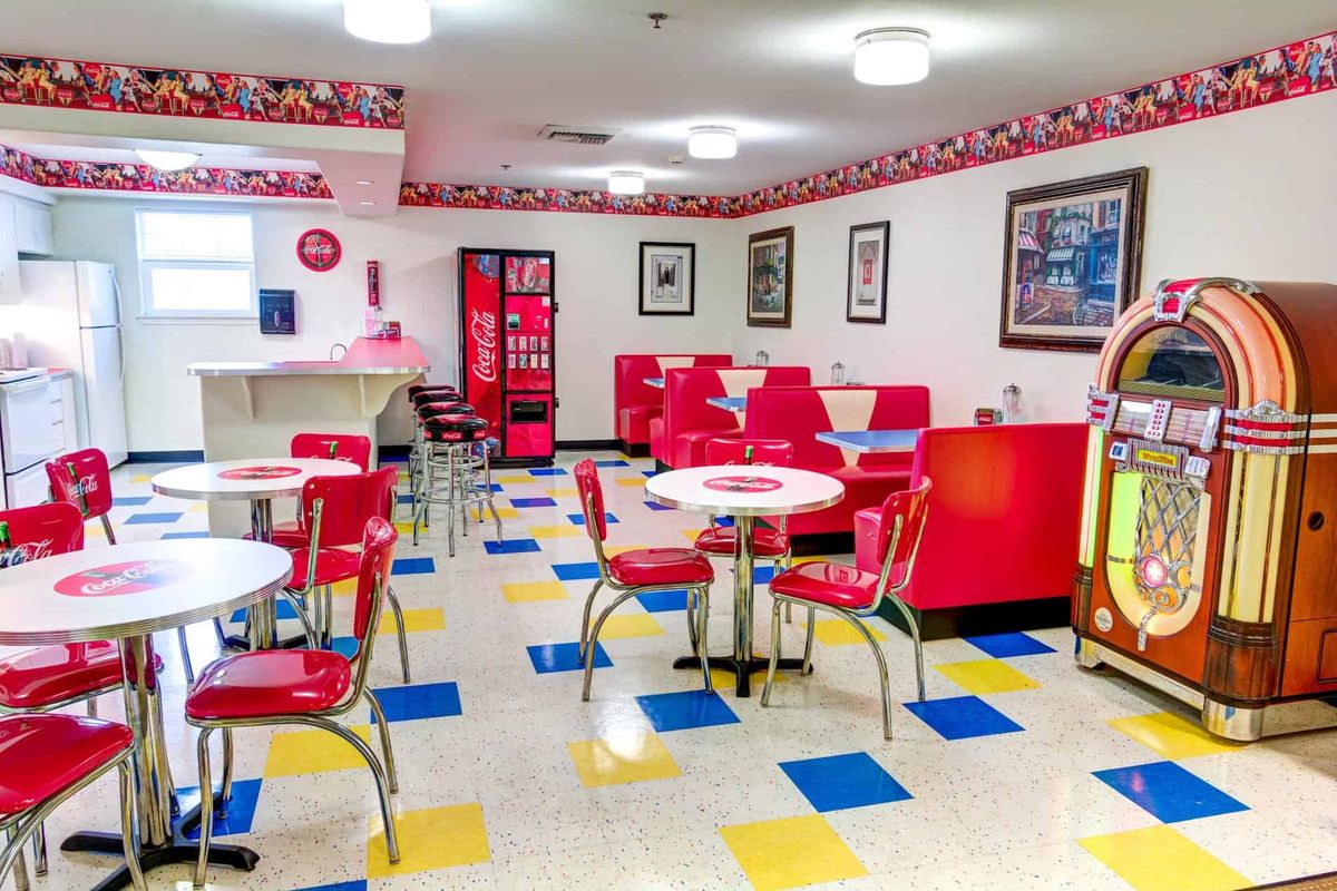 A retro diner with red chairs and a checkered floor, styled in a nostalgic 1950s theme.