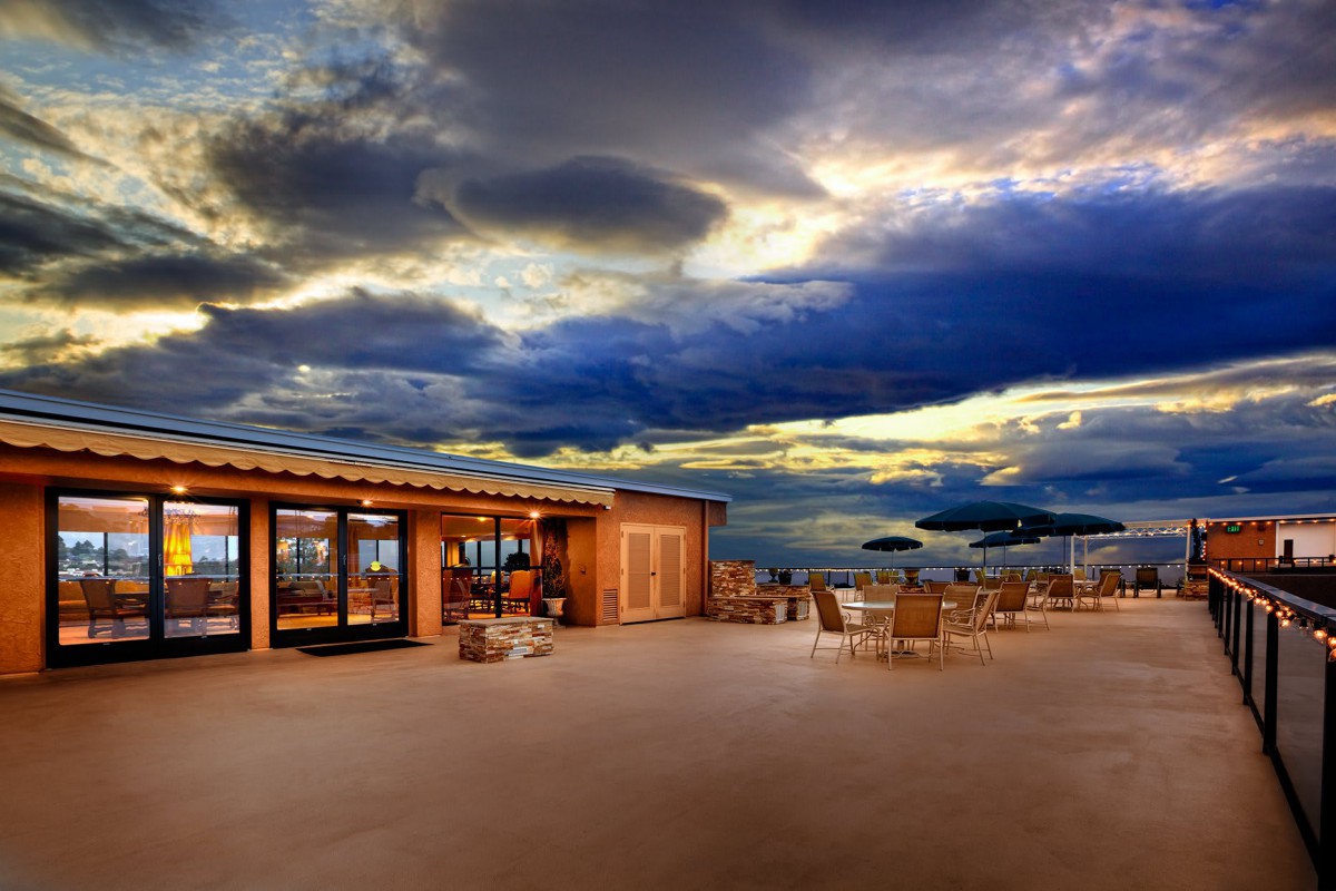 A picturesque outdoor restaurant patio at sunset with dramatic clouds in the sky.