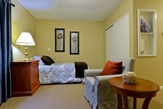 A cozy bedroom with a bed, armchair, and warm lighting.