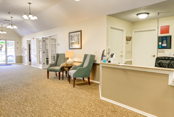 A cozy and neatly arranged reception area with chairs, a counter, and wall decorations.