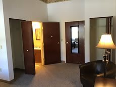 A room interior with multiple doors, a chair, and a lamp.
