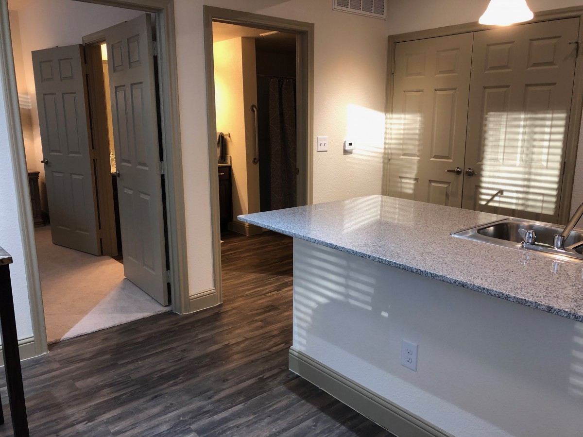A modern apartment kitchen with a marble countertop and hardwood floors.