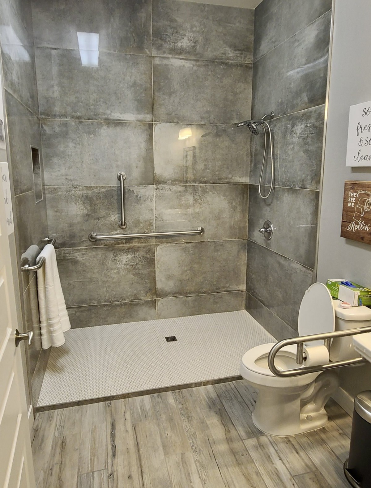 A modern, accessible bathroom with tiled walls and handrails.