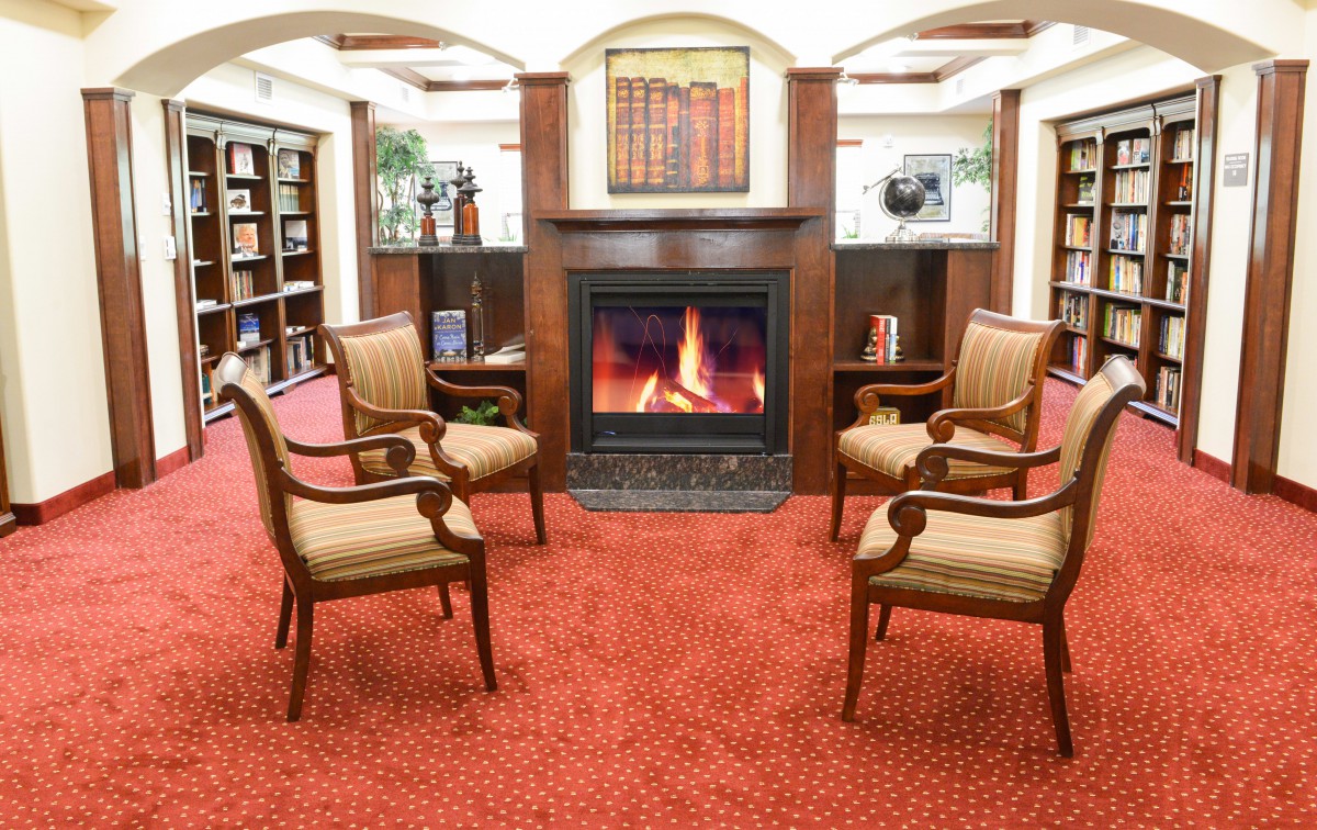 A cozy library seating area with a fireplace and four chairs.