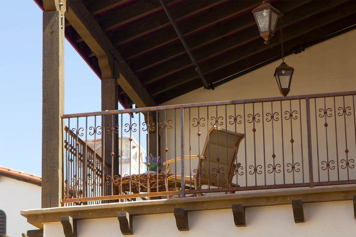 A cozy balcony with a wicker chair and decorative lanterns under a wooden roof.