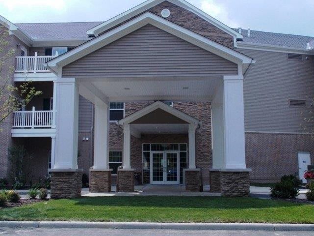 The image shows the entrance of a building with columns and a peaked roof.