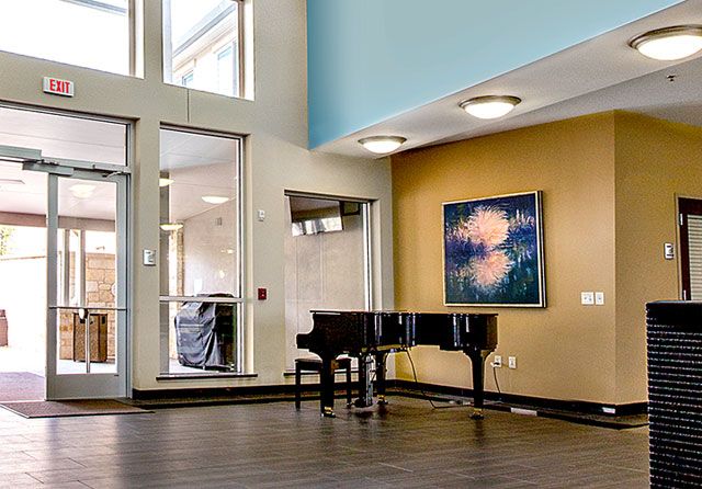 A modern interior with a grand piano and an abstract painting on the wall.