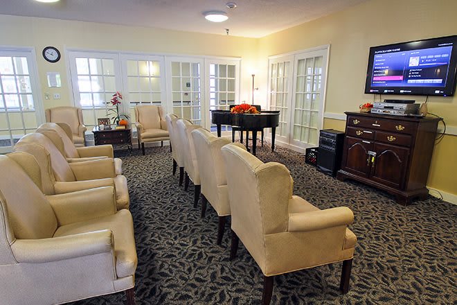 A comfortable lounge with rows of chairs, a piano, and a television.