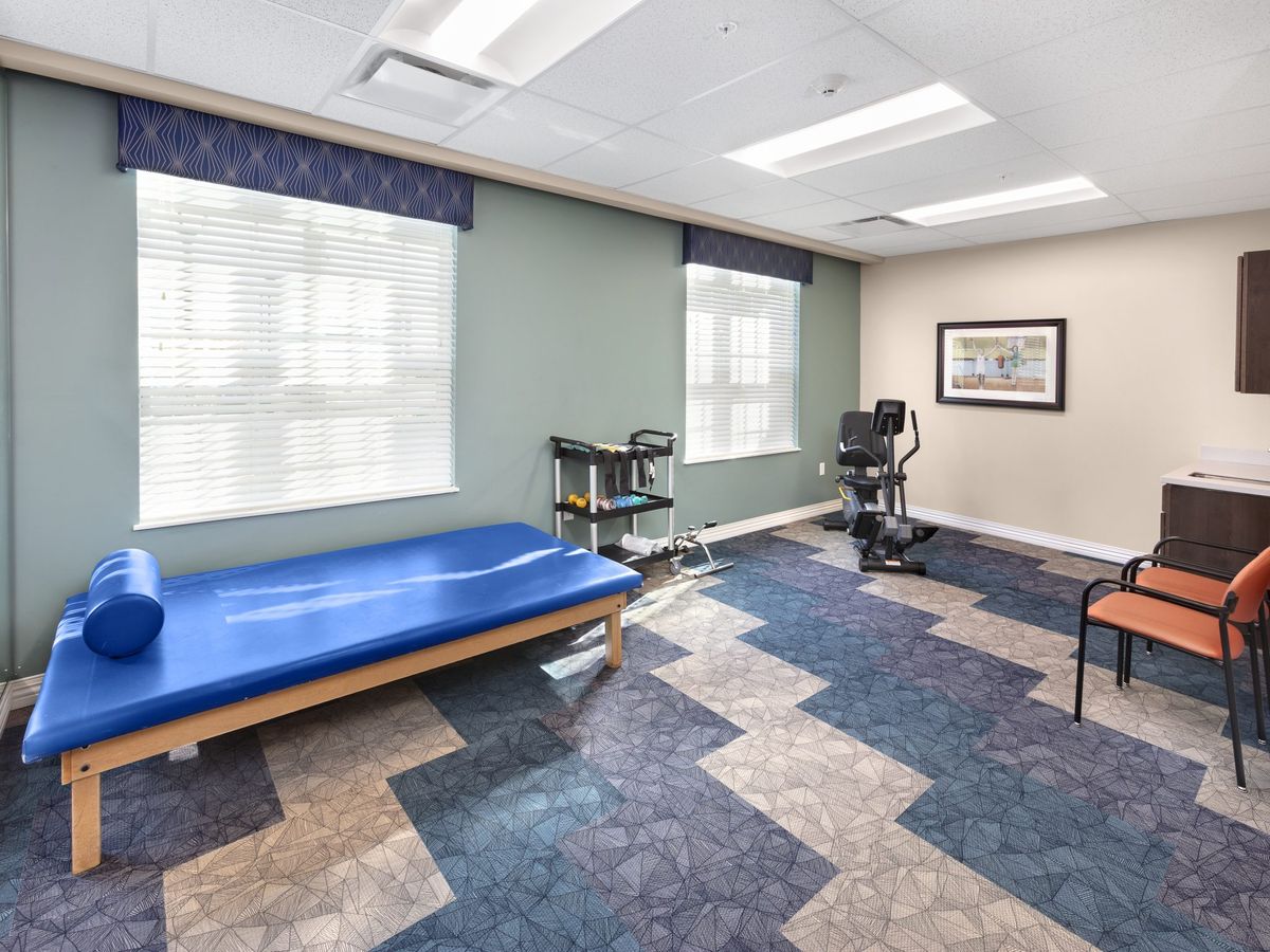A well-lit physical therapy room with a treatment table and exercise equipment.