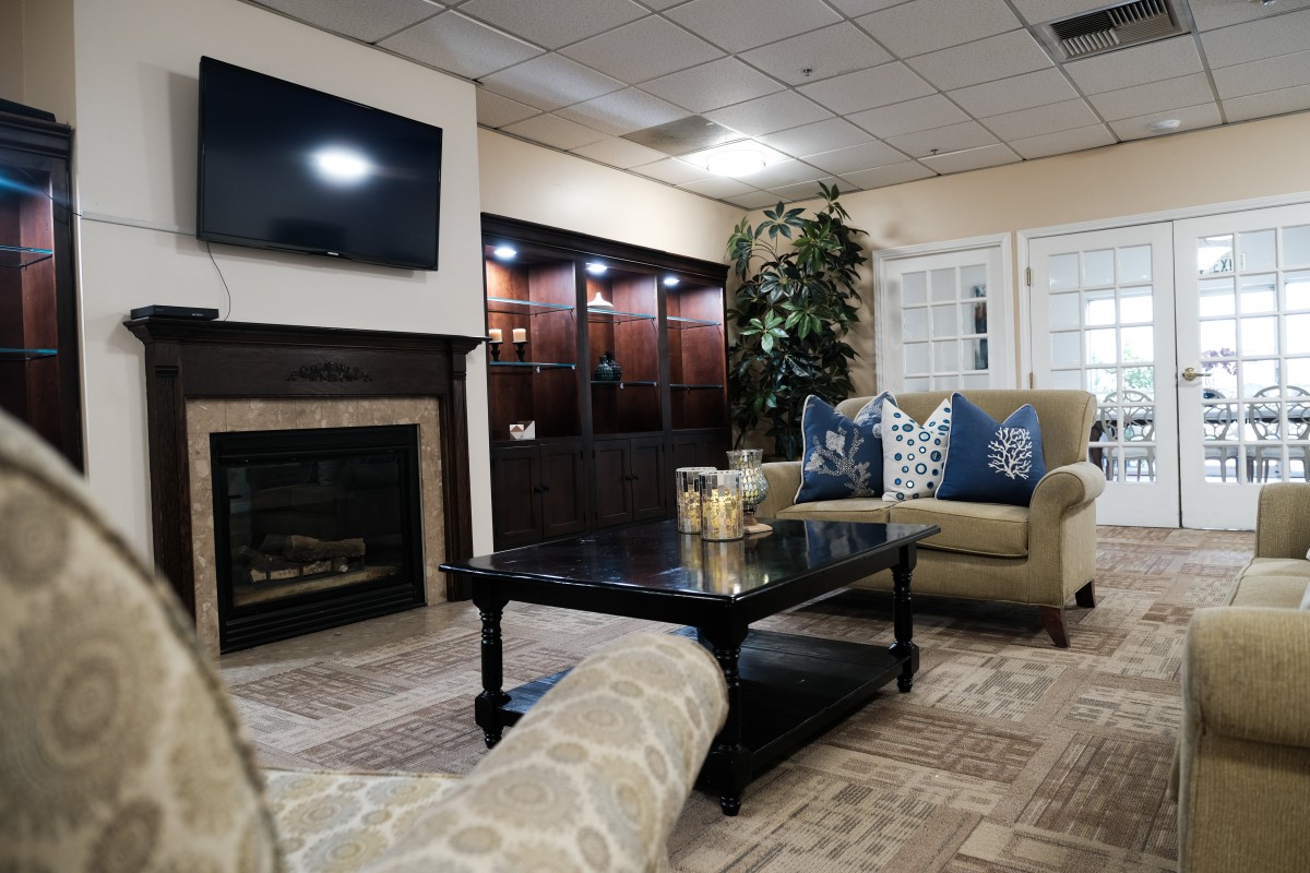 A cozy living room featuring a comfortable couch, a coffee table, and a fireplace with a TV mounted above.