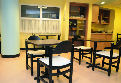 A cozy dining area with black wooden tables and chairs against a warm yellow backdrop.