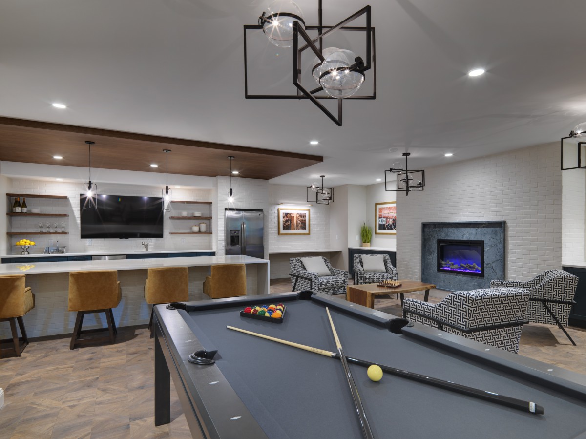 A modern game room featuring a pool table, television, and stylish seating area with decorative lighting.