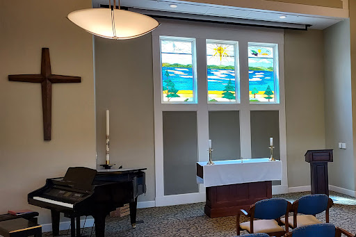A serene chapel interior featuring stained glass windows and a piano.
