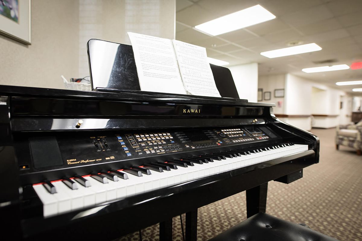 A piano with sheet music displayed on its stand, situated in an indoor setting.
