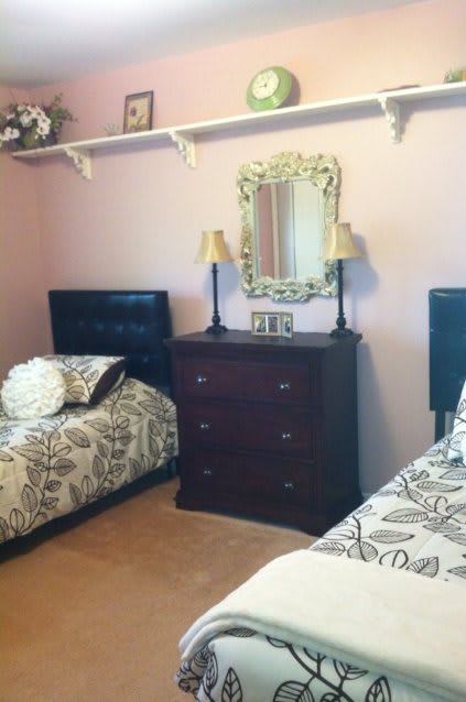 A cozy bedroom with twin beds, a dresser with lamps, and a decorative mirror.