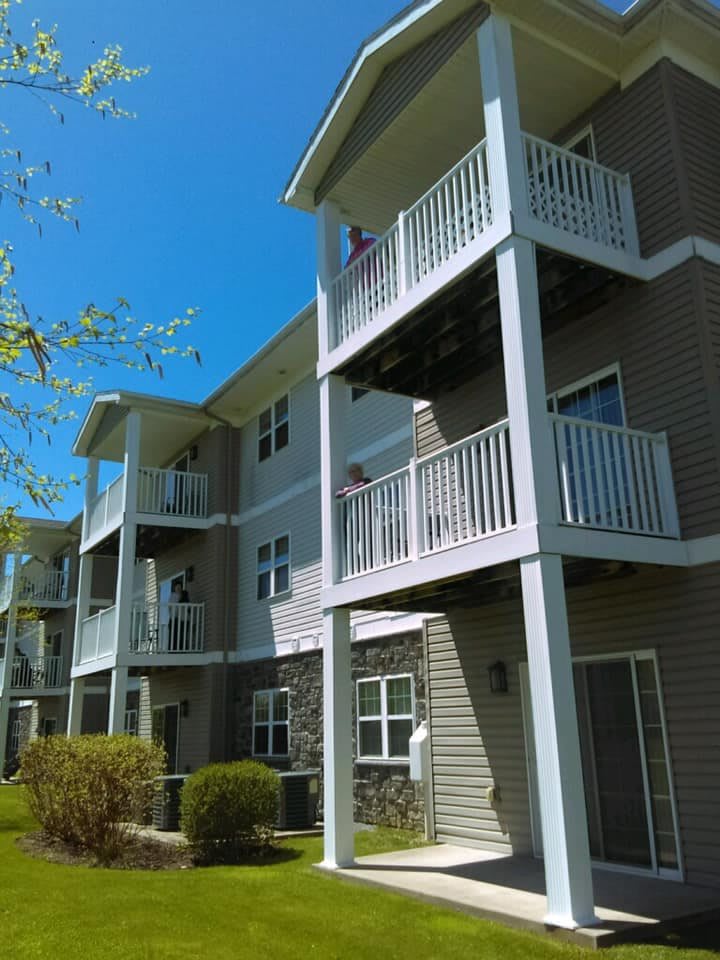 A modern apartment building with multiple balconies under a clear blue sky.