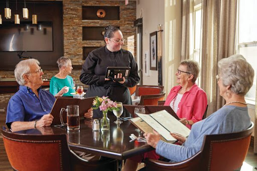 A group of diners are engaged in conversation with a waiter at a restaurant.