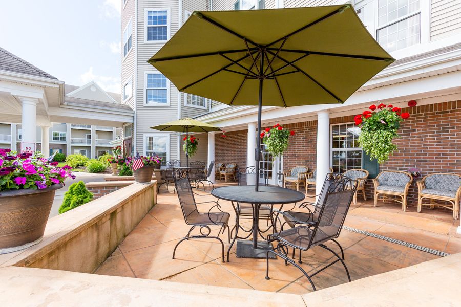 A cozy outdoor patio area with tables, chairs, and umbrellas in front of a building.