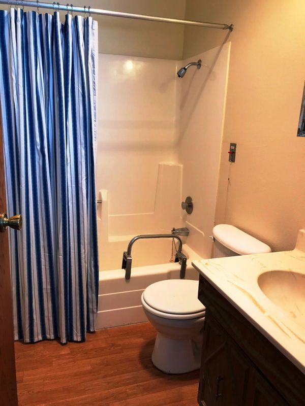 A small bathroom with a shower, toilet, and sink.