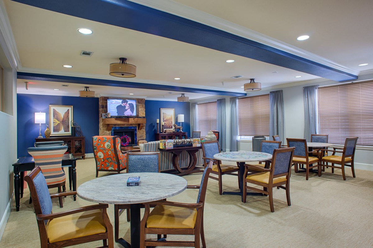 A cozy lounge area with tables, chairs, and a fireplace.