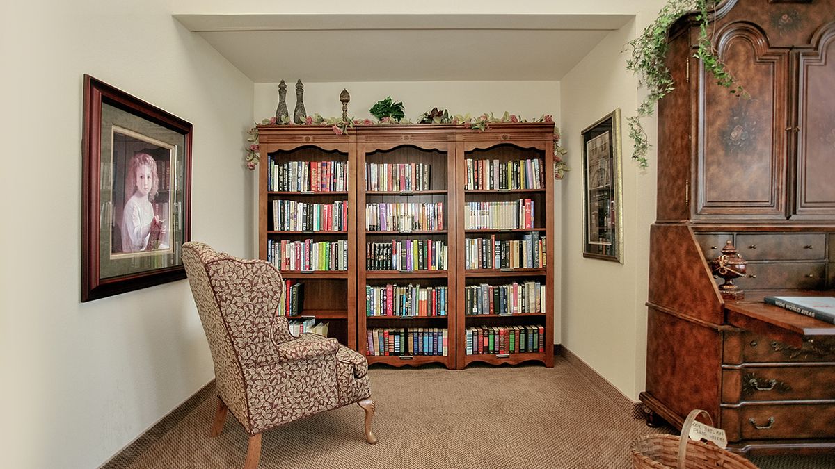 A cozy home library with a comfortable armchair and a wooden bookshelf filled with books.