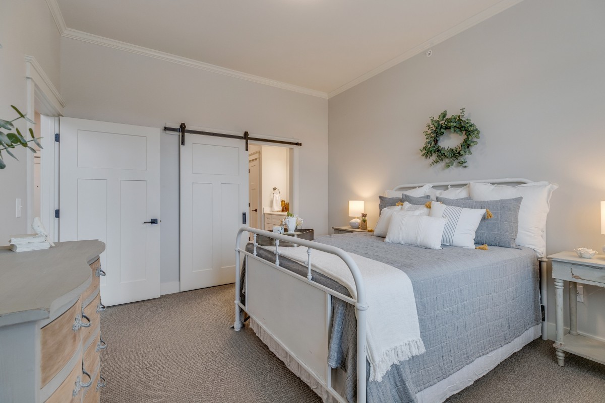 A cozy modern farmhouse bedroom with a stylish bed, barn door, and elegant decor.