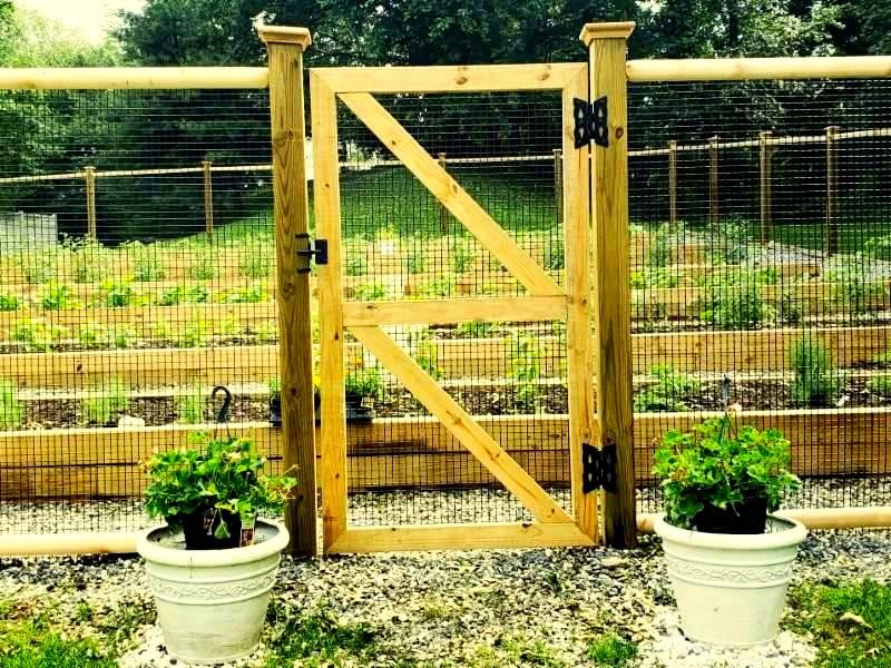 A wooden garden gate with planters on each side, leading to a lush garden.