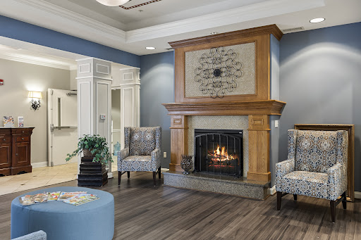A cozy living room featuring a warm fireplace, stylish blue walls, and comfortable seating arrangements.