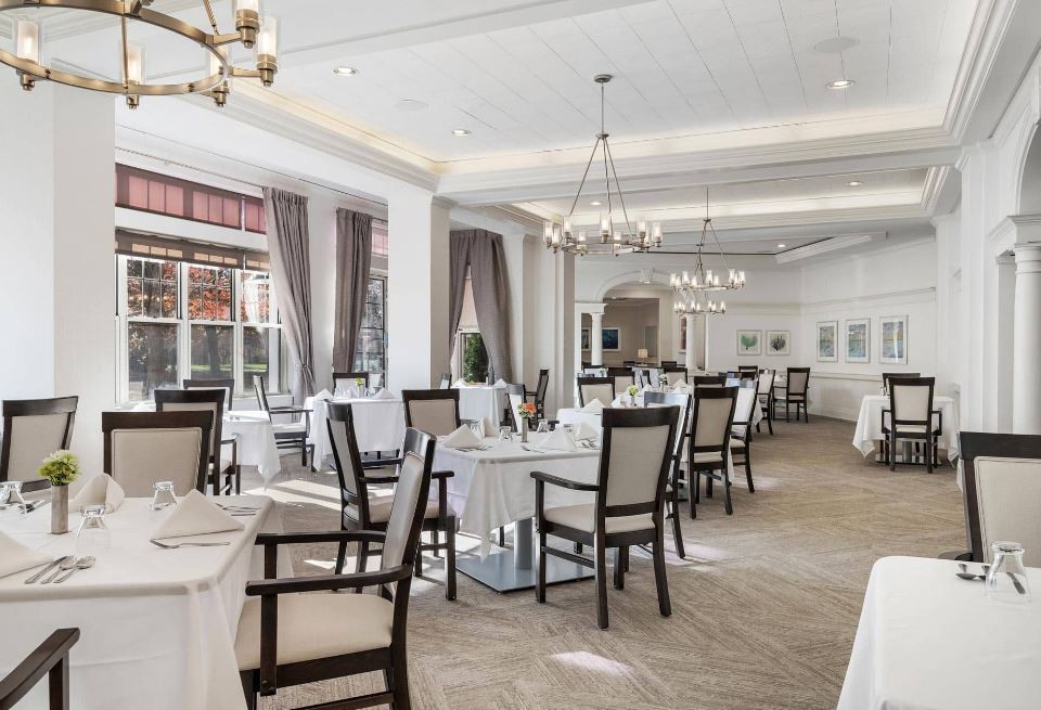An elegant restaurant interior featuring neatly arranged tables and chairs, with chandeliers providing a warm ambiance.