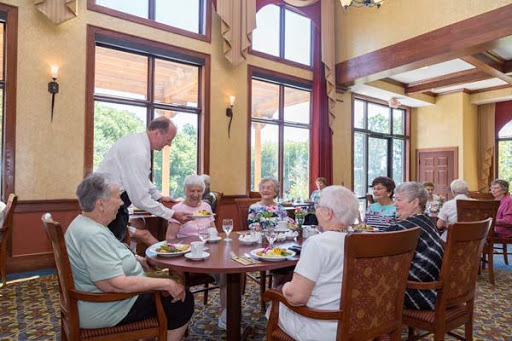 A group of elderly individuals enjoying a meal together in a bright, spacious dining area.