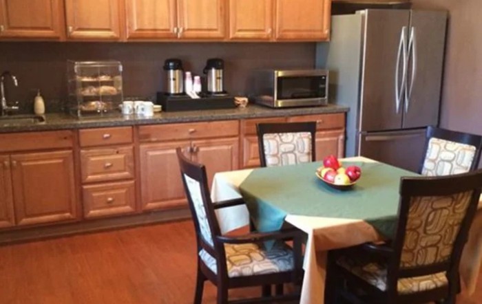 A cozy kitchen and dining area with wooden cabinets, a table with chairs, and various appliances.