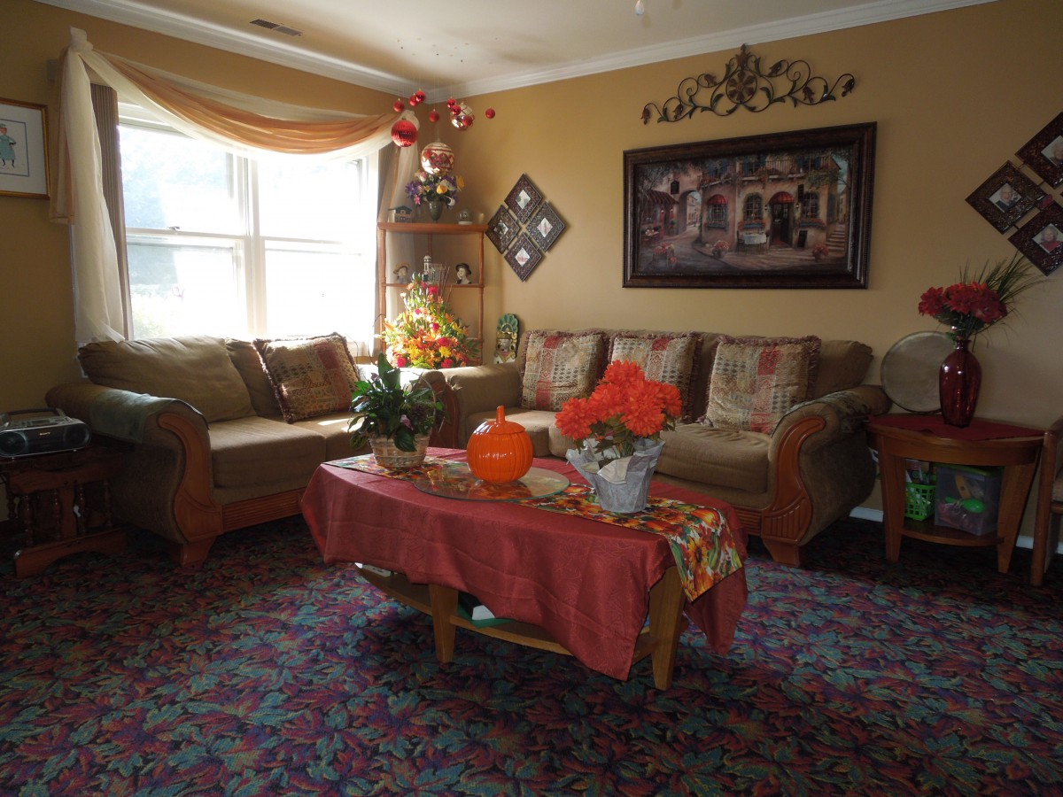 A cozy living room with a large sofa, coffee table adorned with plants and decorations, and wall art enhancing the decor.