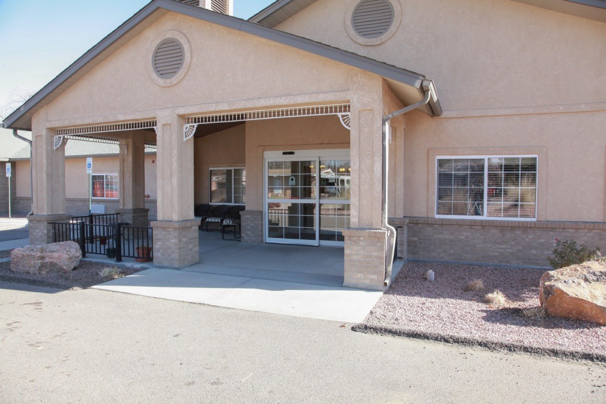 A building with a covered entrance and a sidewalk leading to the door.