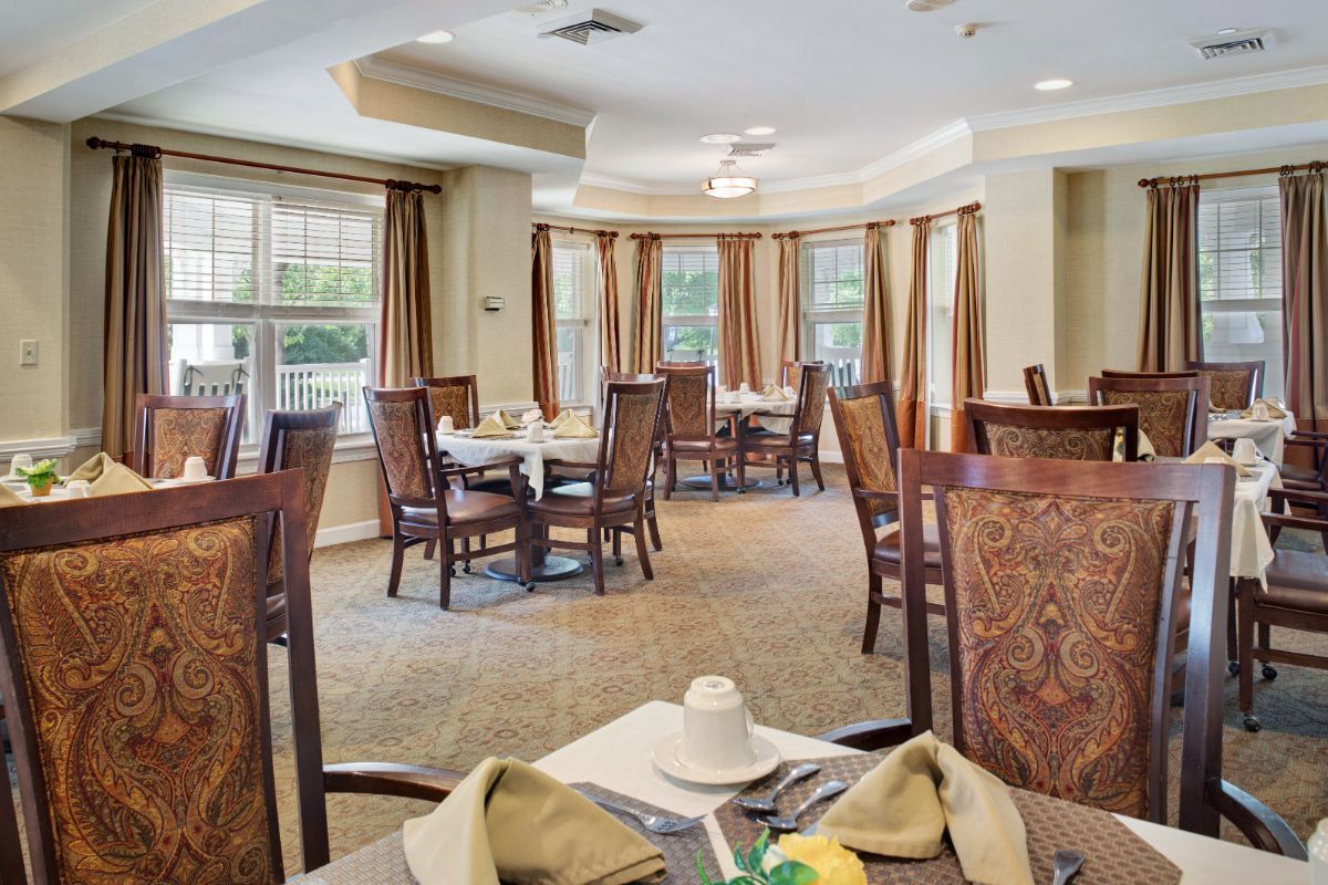 Elegant dining area with neatly arranged tables and chairs, featuring large windows for natural light.